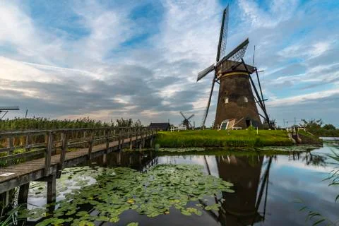 Operational windmill servicing its duty under a warm cloudy and sunny weather 库存照片