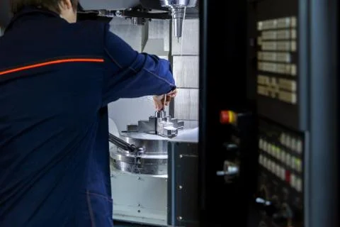 The operator of 5-axis cnc milling machine changes the workpiece in a collet  Stock Photos