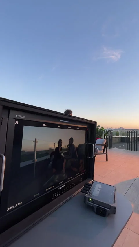 Operator adjusts camera around pair of colleagues at terrace table Stock-Footage 303060232