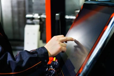 Operator adjusts CNC machine using touch screen Stock Photos