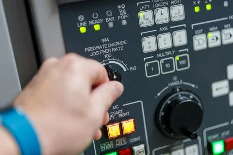 Operator adjusts feed rate on machine control panel during production proce.. 스톡 사진