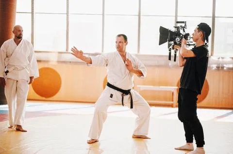 Operator with big camera shoots karate training on tatami Stock Photos
