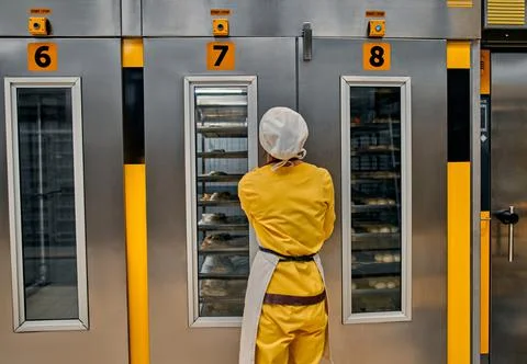 Operator with bread dough trays, ready to be placed in factory ovens. Bread b Stock Photos
