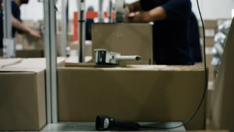 An operator builds a cardboard box with adhesive tape in a warehouse. The operat Video stock 128294776