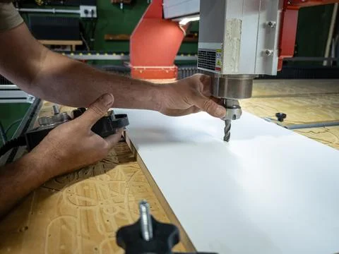 Operator calibrating CNC router spindle z axis zero probe sensor on wood pane Stock Photos
