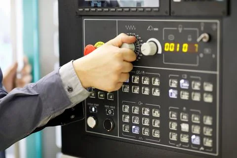 Operator changes settings of the CNC machine Stock Photos