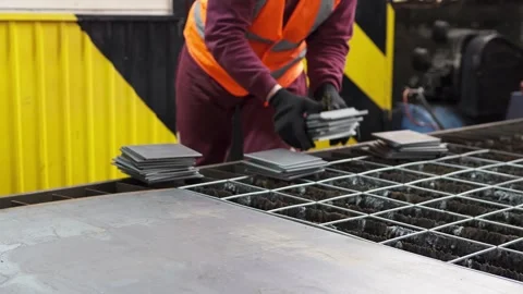 An operator of a CNC machine for plasma metal cutting collects cut metal parts. Stock Footage 274132959