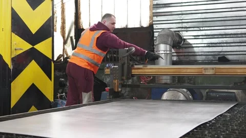An operator of a CNC plasma cutting machine cleans the work surface. Stock Footage 276549829