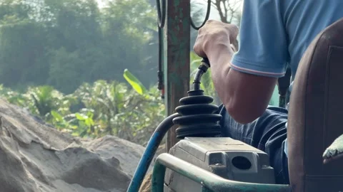 An operator controls an excavator while lifting sand with a bucket for loading Stock Footage 331865999