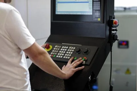 Operator controls industrial CNC machining center Stock Photos