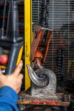 Operator controls overhead electric chain hoist crane lifting heavy machine.. Stock Photos