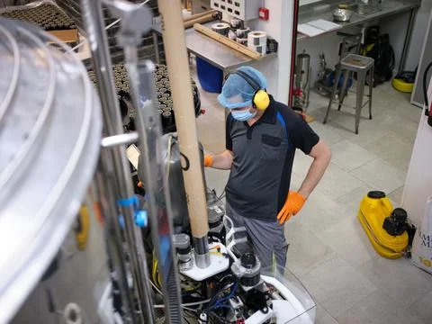 Operator of a craft beer brewery working with a machine Stock Photos