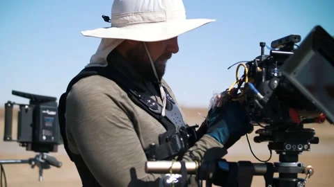 The operator in the desert adjusts the video camera.  Movie production Stock Footage 226582465