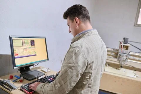 Operator Entering Coordinates on Computer for CNC Machine to Precisely Cut... Foto stock