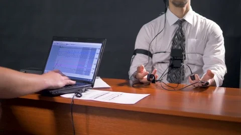 An operator examines lie detector graphs beside a deeply breathing subject. 4K. Stock Footage 78284535