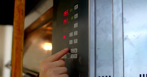 Operator fingertip pressing commercial oven control panel with illuminated Stock Footage 344582470