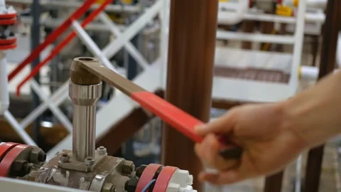Operator in gas industry is seen closing valve on pipeline. Operational Stock Footage 282869163