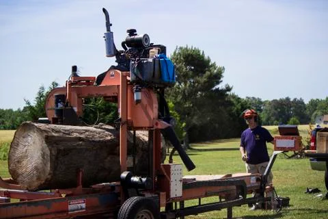 Operator guides blade into log on portable sawmill  스톡 사진
