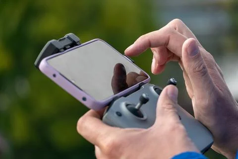The operator holds the remote control of the drone in his hands. A farmer use Stock Photos