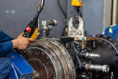 Operator maneuvers overhead crane pendant control to position heavy machine.. Stock Photos