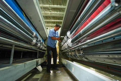 Operator Patrolling Mechanical Rollers in the Passage of Printing Equipment Stock Photos
