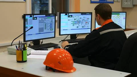 Operator at plant control panel monitors parameters of equipment at plant Stock Photos