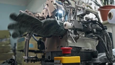 Operator positions glove with precision. Machine processes cuff edge. Stock Footage 344971644