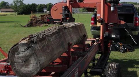 Operator positions log on rail of portable sawmill Stock Footage 40472210
