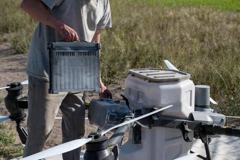 Operator replacing battery of agricultural drone. Stock Photos
