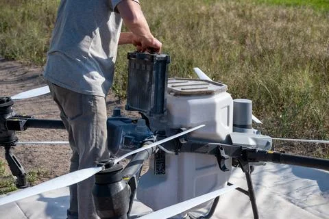 Operator replacing battery of agricultural drone. Stock Photos