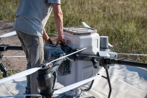 Operator replacing battery of agricultural drone. Stock Photos
