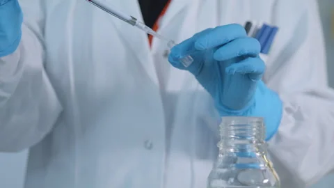 Operator in a research lab pours liquid into glass vials 動画素材 274351285