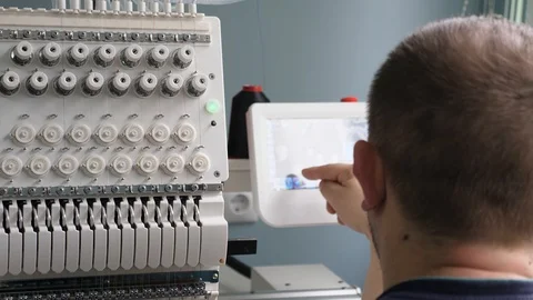 The operator sets up the cnc machine. A worker is programming a sewing machine 库存影片 119237997