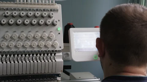 The operator sets up the cnc machine. A worker is programming a sewing machine 库存影片 119937037