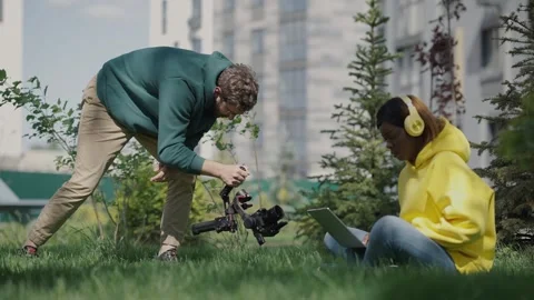 Operator with stabilizer in his hands takes video of dark-skinned girl sitting Stock Footage 244268567