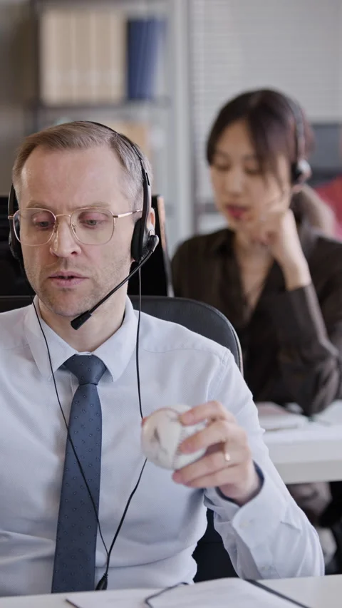 Operator Talking to Client via Headset in Office with Colleague in Background 스톡 동영상 335752100