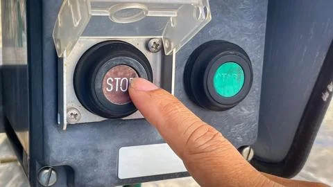 Operator technician hand pressing the stop button on a local control switch.. Stock Photos