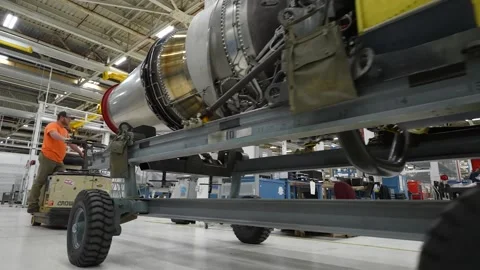 Operator transporting aircraft engine part in engine overhaul facility Stock Footage 231690674