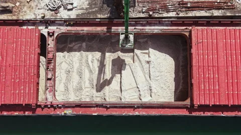 Operator uses crane to unload cargo from red ship at dock during daytime in a Stock Footage 337914349