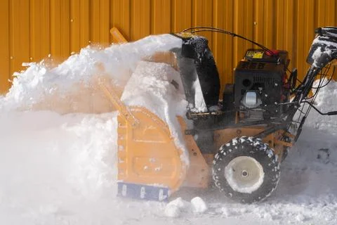 Operator is using snow blower to clear snow after winter storm, with snowblower Stock Photos