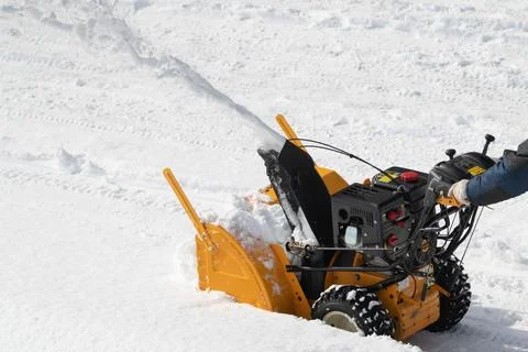 Operator using snow blower to remove snow from road after winter storm Foto stock
