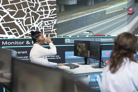 Operator wearing headset drinks from cup while watching traffic movement Stock Photos