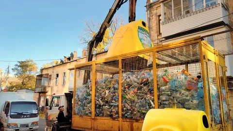 Operator of a yellow plastic garbage truck unloads trash and plastic bottles Stock Footage 120441219