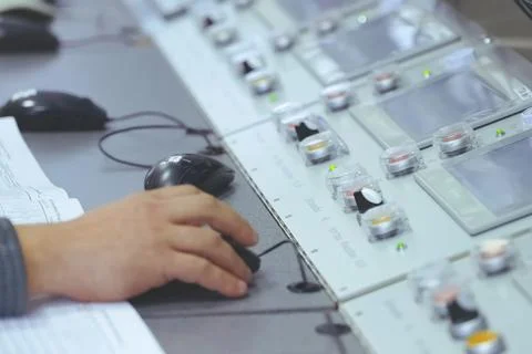 The operator's hand holds a computer mouse at the control panel of the plant' Stock Photos