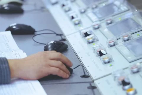 The operator's hand holds a computer mouse at the control panel of the plant' Stock Photos