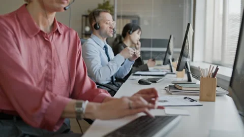 Operators in Headsets Using Computers Consulting Clients in Call Center Stock Footage 335754534