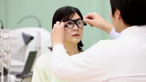 Ophthalmologist Adjusting Trial Frames on Female Patient During Vision Test Vídeos de archivo 344238232