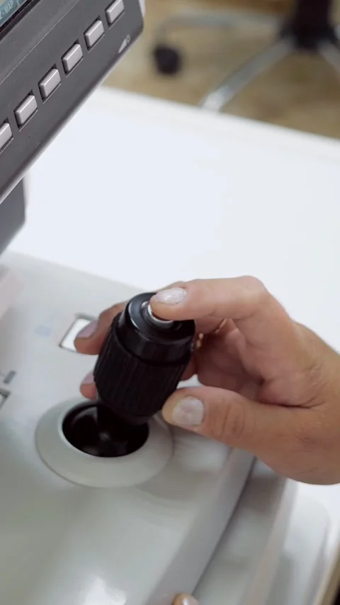Ophthalmologist operating autorefractor joystick for vision test, focusing on Stock Footage 341429689
