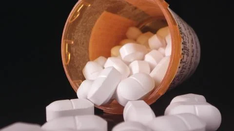 Opioids lying on black table top with open bottle Stock Photos