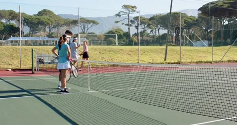 Opposing doubles teams exchanging handshakes at net on hard court after match Stock Footage 335568562